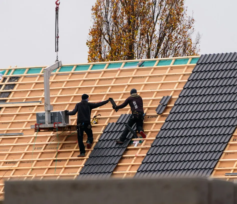 Zwei Dachdecker verlegen Ziegel auf einem Neubau